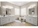 Spa-like bathroom with dual vanities, a freestanding tub, glass block windows, and modern lighting fixtures at 2264 Savannah River St, Henderson, NV 89044