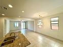 Open-concept living space with tile flooring, natural light, and view of kitchen at 7253 Blooming Jasmine Ave, Las Vegas, NV 89117