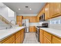 Well-lit kitchen features stainless steel appliances, wood cabinets, light countertops and tiled floors at 9785 Gallo Dr, Las Vegas, NV 89147
