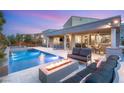 Stunning backyard oasis featuring a modern pool, spa, fire pit, and ample seating for outdoor entertaining at 10482 Calico Terrace Ave, Las Vegas, NV 89135