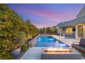 Backyard pool with a modern fire pit, patio area and lush landscaping creates an ideal outdoor oasis at 10482 Calico Terrace Ave, Las Vegas, NV 89135