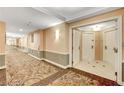 Long hallway featuring neutral walls with decorative carpets, lighting, and multiple entry doors for residential units at 125 E Harmon Ave # 1620, Las Vegas, NV 89109