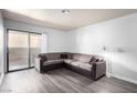 This living room features gray wood-look flooring, a neutral sectional couch, and sliding glass door to a patio at 2451 N Rainbow Blvd # 1016, Las Vegas, NV 89108