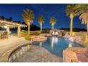 Custom pool with rock waterfall, spa, and swim up bar, all illuminated at twilight at 382 Chaplin Cove Ave, Las Vegas, NV 89183