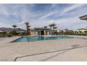 Sparkling community pool with a spacious deck area surrounded by palm trees, creating a resort-like atmosphere at 6804 Sage Gold Ct, North Las Vegas, NV 89086