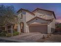 Stucco home with a two-car garage and brick paver driveway at dusk at 7060 Seat Wall Rd, Las Vegas, NV 89148