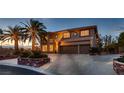 Elegant two-story home at dusk with palm trees, three-car garage and a circular driveway at 8396 Garnet Canyon Ln, Las Vegas, NV 89129