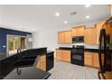 Modern kitchen with wooden cabinets, black appliances, and a breakfast bar overlooking the living area at 3528 Tack St, Las Vegas, NV 89122