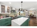 A kitchen featuring green cabinets, white countertops, modern appliances, tile backsplash and wood flooring at 5492 Royal Vista Ln, Las Vegas, NV 89149