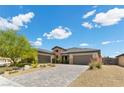 Beautiful home featuring a three-car garage, lush landscaping, and a brick driveway at 7477 Triple Knot Ct, Las Vegas, NV 89113