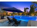 A beautiful swimming pool is surrounded by lush landscaping and a patio with lounge chairs at 7477 Triple Knot Ct, Las Vegas, NV 89113