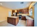 Kitchen featuring stainless steel appliances, dark wood cabinets, and granite countertops at 9651 Bouncing Ball St, Las Vegas, NV 89178