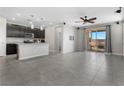 Open-concept living room and kitchen area featuring tile flooring, stainless appliances, and sliding glass doors to a patio at 2293 Teatro Ave, Henderson, NV 89044