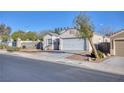 Single-story home featuring a two-car garage, low maintenance landscaping, and mature trees at 3197 Castle Canyon Ave, Henderson, NV 89052