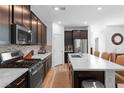 Modern kitchen with stainless steel appliances, dark wood cabinets, and white quartz countertops on the island at 4368 Latitude Valley Ct, North Las Vegas, NV 89084