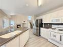 Well-equipped kitchen with stainless steel appliances, white cabinets, and an island with a sink at 504 Landra Ln, Henderson, NV 89015