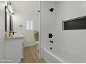 Stylish bathroom with white textured tiles, black fixtures, and a shower over tub at 613 Kings Pl, Boulder City, NV 89005