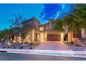Contemporary home with a brick driveway, well-manicured landscaping, and a three-car garage at 7 Hilltop Crest St, Henderson, NV 89011
