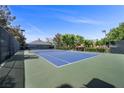Outdoor tennis court featuring a blue court surface and well-maintained green surroundings at 7460 Grassy Field Ct, Las Vegas, NV 89131