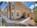 Exterior view of a two-story townhouse showcasing stucco facade, arched windows, and well-maintained landscaping at 9655 Lame Horse Dr, Las Vegas, NV 89123