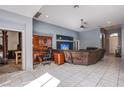A spacious living room area with tile flooring, ceiling fan, and an open doorway to an adjacent room at 9831 Running Rabbit St, Las Vegas, NV 89143