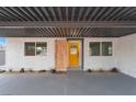 Inviting covered front porch with a custom wood door, modern lighting, and xeriscaped yard at 1808 E Saint Louis Ave, Las Vegas, NV 89104