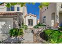 Close up shot of the charming stucco home's front entrance with gated walkway and landscaping at 2212 Warm Walnut Dr, Las Vegas, NV 89134