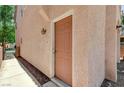 Side view of a peach stucco home featuring a solid front door with detailed trim and a walkway at 5588 Ness Ave, Las Vegas, NV 89118