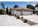 Exterior view of a three car garage with a large driveway and minimal landscaping at 7660 Descanso Ln, Las Vegas, NV 89123