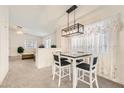 Cozy dining area with modern lighting fixture, seating for four, and large windows at 5114 Mascaro Dr, Las Vegas, NV 89122