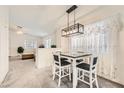 Open dining area with modern light fixture, table with four chairs, adjacent to the living room at 5114 Mascaro Dr, Las Vegas, NV 89122