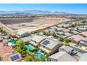 Stunning aerial view of the home with backyard pool and solar panels with mountain backdrop at 8303 Saddleback Ledge Ave, Las Vegas, NV 89147
