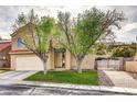 Charming two-story home with well-manicured lawn, driveway to side gate and mature trees in front yard at 421 Raindance Dr, Henderson, NV 89014