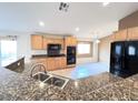 Granite countertops and black appliances highlight this kitchen with breakfast bar and tile flooring at 8161 Cane Creek Mill Ct, Las Vegas, NV 89131