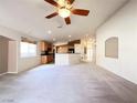 Spacious living room with neutral carpet, ceiling fan, and open floor plan to the kitchen at 8161 Cane Creek Mill Ct, Las Vegas, NV 89131