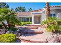 Beautiful home featuring a charming entrance with stone steps and lush tropical landscaping at 9524 Quail Ridge Dr, Las Vegas, NV 89134