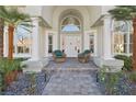 Elegant front entrance with a grand archway, white columns, and decorative chairs flanking the doorway at 2338 Dolphin Ct, Henderson, NV 89074