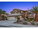 Elegant two-story house with landscaped front, showcasing a three-car garage, stone accents and lush palm trees at 283 Grand Olympia Dr, Henderson, NV 89012