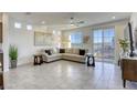 Bright living room with tile floors, large windows, a ceiling fan, and a comfortable sectional sofa at 5368 Knitmore Ct, Las Vegas, NV 89139