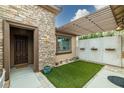 Inviting entrance featuring stone accents, a pergola, and a cozy artificial turf area at 5265 Lucca Ln, Pahrump, NV 89061