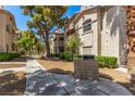 Exterior condo view with a sidewalk leading past lush trees, next to a grill at 6480 Annie Oakley Dr # 814, Las Vegas, NV 89120