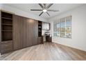 A cozy bedroom features light wood-look floors, a ceiling fan, and a built-in Murphy bed with desk and shelving at 7058 W Camero Ave, Las Vegas, NV 89113