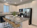 Modern kitchen featuring white cabinets, granite countertops, stainless steel appliances, and a large island with seating at 9159 Oxford Blue Ave, Las Vegas, NV 89148