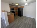 Well-lit kitchen with black appliances, wood cabinetry and wood-look tile flooring at 7701 W Robindale Rd # 127, Las Vegas, NV 89113