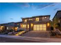 Elegant two-story home featuring a modern garage door, desert landscaping, and inviting front entrance with lit stairs at 395 Prairie Sun St, Las Vegas, NV 89138