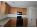 Well-lit kitchen showcasing wooden cabinets, black appliances, and a functional layout for cooking at 520 Shire Hall St, Las Vegas, NV 89178