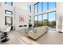 Sunlit living room with floor-to-ceiling windows, a fireplace, and modern decor at 10756 Steel Ridge Ct, Las Vegas, NV 89135