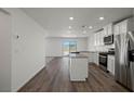 Open-concept kitchen with stainless steel appliances, white cabinetry and island with breakfast bar seating at 2636 Lily Point St, Las Vegas, NV 89156