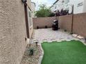 Paver patio with synthetic grass featuring a barbecue grill, enclosed by a privacy wall at 355 Gracious Way, Henderson, NV 89011