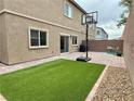 Private backyard featuring low-maintenance artificial turf, brick-paved patio, and a basketball hoop for recreation at 7041 Fossil Rim St, North Las Vegas, NV 89084